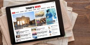 Tablet placed on a newspaper with a screen of today's news